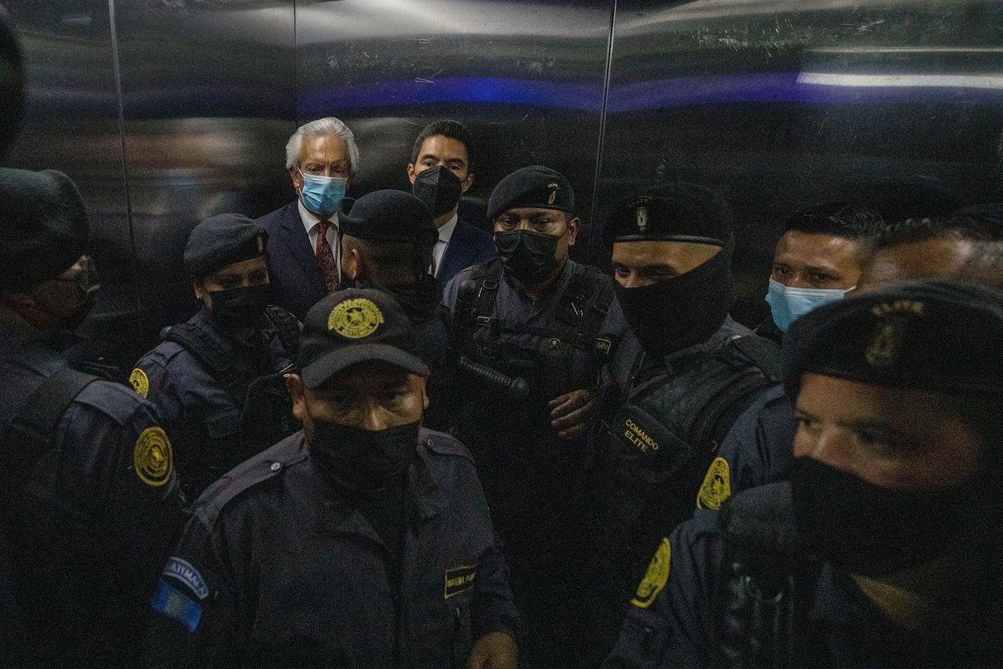 José Rubén Zamora, con mascarilla, rodeado de policías dentro de un ascensor.