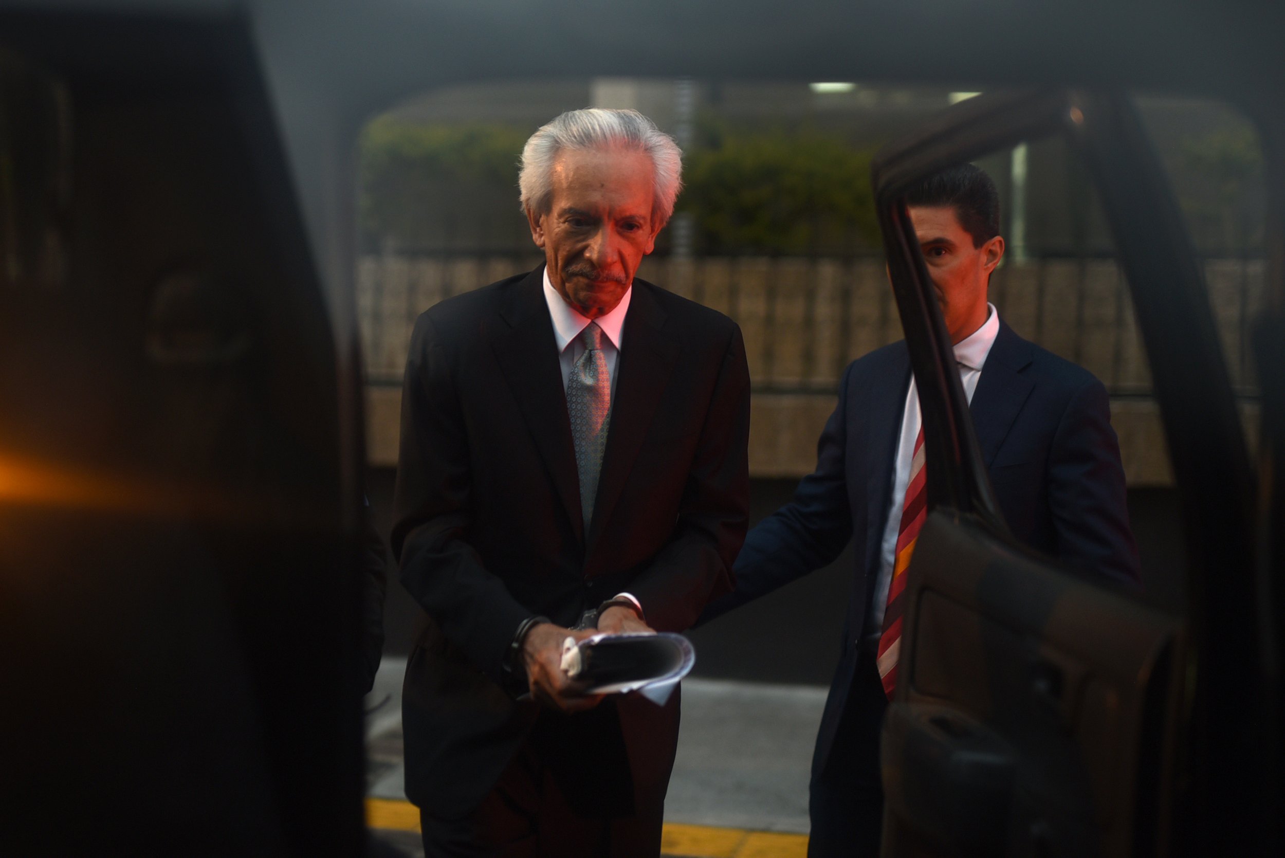 José Rubén Zamora, esposado, es subido a un vehículo al anochecer.